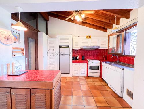 une cuisine avec des placards blancs et un comptoir rouge dans l'établissement Maison Porticcio centre, à Grosseto-Prugna