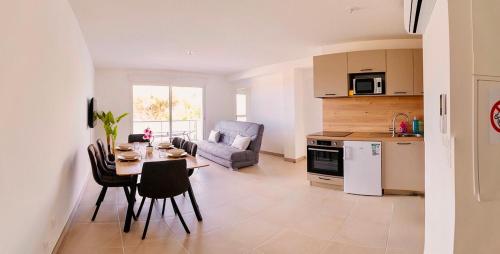 une cuisine et un salon avec une table et des chaises dans l'établissement LE 209, 3min à pieds de la Plage, tout confort, Terrasse, 2 Parking privée, à Vias