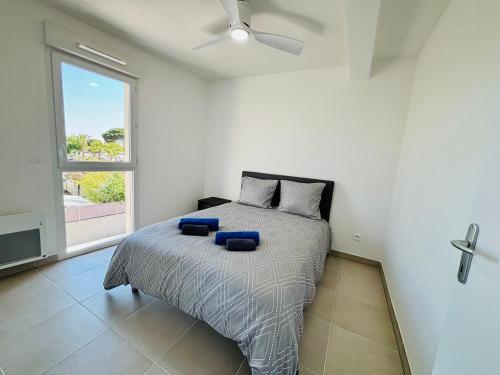 une chambre avec un lit avec des oreillers bleus et une fenêtre dans l'établissement LE 209, 3min à pieds de la Plage, tout confort, Terrasse, 2 Parking privée, à Vias