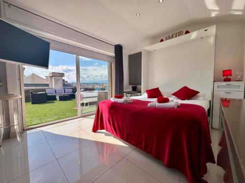 a bedroom with a bed with red sheets and a large window at Studio Love Room Rooftop Jacuzzi SCLS Rentals in Cannes