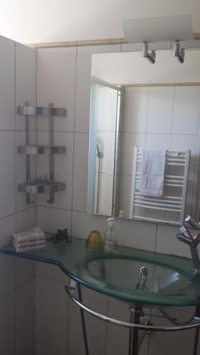 La salle de bains est pourvue d'un lavabo en verre et d'un miroir. dans l'établissement Appart Ensoleillé Proche Remparts, à Avignon