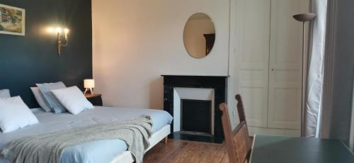 a bedroom with a bed and a fireplace and a table at Family home Cour du Louvre in Saint-Sever-Calvados