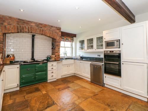 a kitchen with white cabinets and green appliances at Burrs Farm in Buxton