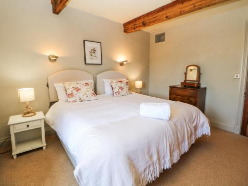 a bedroom with a large white bed and a mirror at Burrs Farm in Buxton