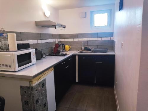 une petite cuisine avec un micro-ondes et un évier dans l'établissement La tranquillité, à Bourges
