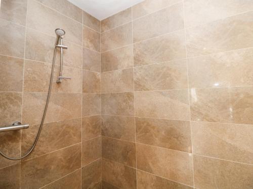 a shower in a bathroom with brown tiles at Burrs Farm in Buxton