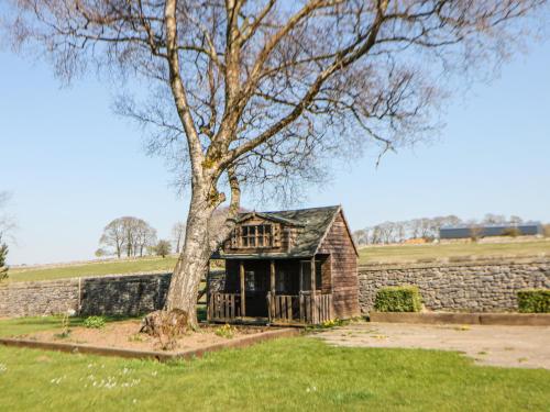an old stone house with a tree in a field at Burrs Farm in Buxton