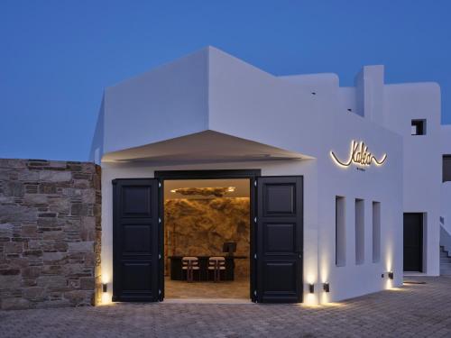 a white building with black doors and chairs at Kalea Mykonos in Ornos
