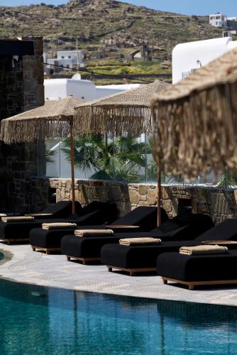 a row of lounge chairs next to a swimming pool at Kalea Mykonos in Ornos