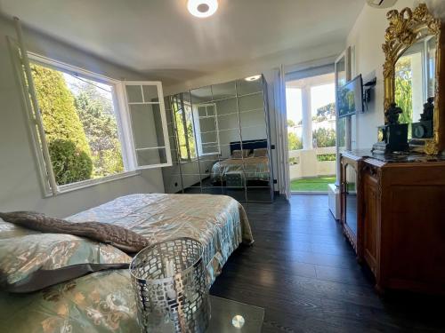 une chambre avec un lit, une commode et un miroir dans l'établissement Un Joyau vue Mer Cap d'Antibes Piscine Body Fitness Sauna & Plage, à Antibes