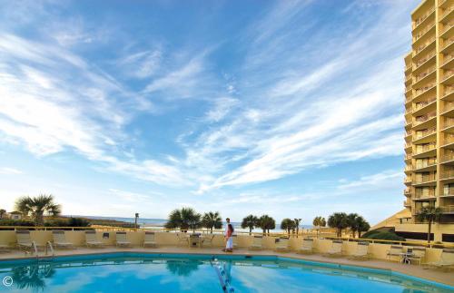 a person standing next to a swimming pool at a resort at Ocean Creek Resort in Myrtle Beach