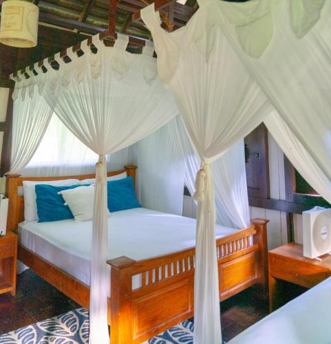 a bedroom with a canopy bed with white drapes at Red Frog Bungalows Ocean Resort in Short Cut