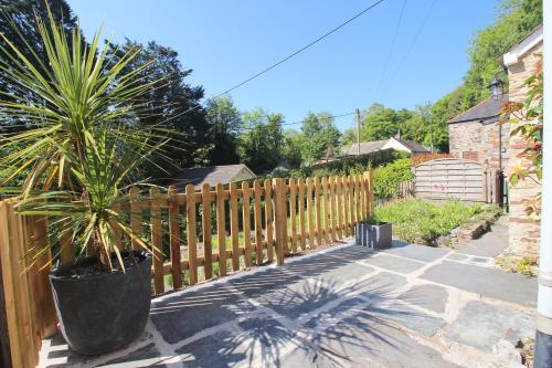 a wooden fence with a potted plant on a patio at Idyllic Cottage near Padstow in Little Petherick