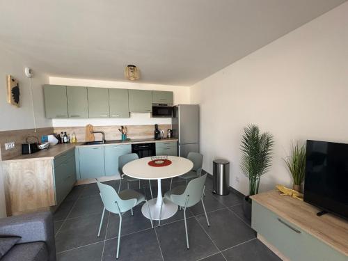 une cuisine avec une table et des chaises dans une pièce dans l'établissement Appartement dans résidence avec piscine, à Calvi