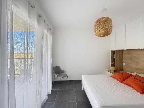 a bedroom with a bed and a chair and a window at Appartement dans résidence avec piscine in Calvi
