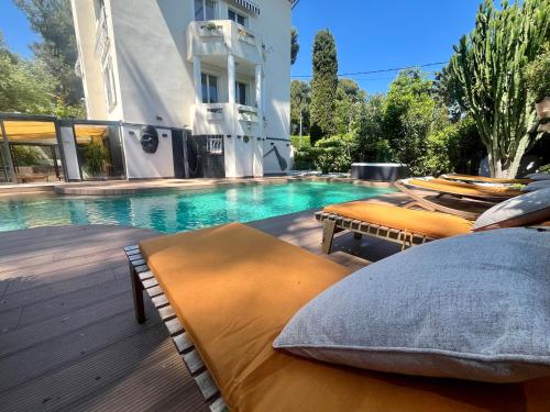 - une piscine avec 2 lits à côté d'un bâtiment dans l'établissement Un Joyau vue Mer Cap d'Antibes Piscine Body Fitness Sauna & Plage, à Antibes