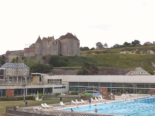 une grande piscine avec un château en arrière-plan dans l'établissement Camping Le clos Savoye, à Biville-sur-Mer
