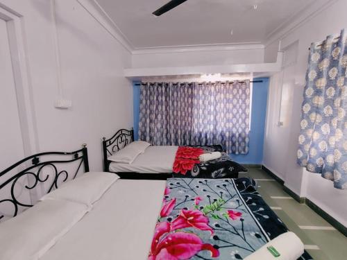 a bedroom with two beds and a window at Mangallam Guest House in Pune