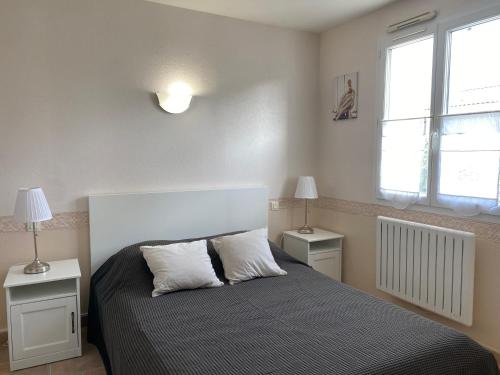 une chambre avec un lit avec deux tables et deux lampes dans l'établissement Agréable maison, aperçu mer, wifi, à La Tranche-sur-Mer