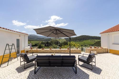 a patio with two chairs and an umbrella at Cavalo de Tróia Villas in Cadaval