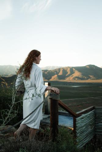 a woman in a white dress standing on a fence at Khanyisa Mountain Lodge in Robertson