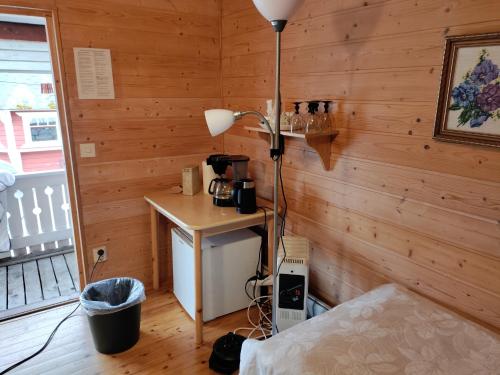a room with a wooden wall with a desk and a lamp at Maatilamatkailu Jänisvaara aittahuoneet in Kolinkylä