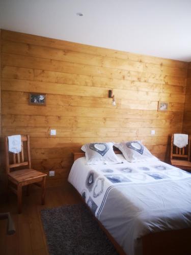 ein Schlafzimmer mit einem Bett und einer Holzwand in der Unterkunft La Crosette in La Thuile