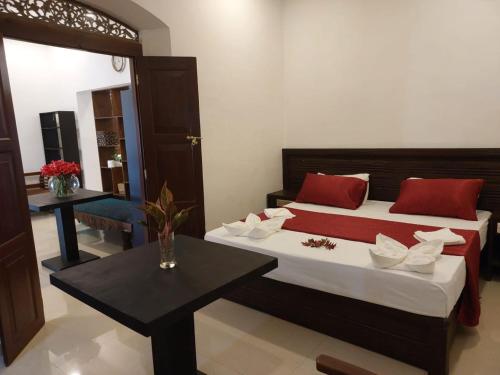 a bedroom with a bed with red pillows and a table at Das Haus Villa & Restaurant in Unawatuna