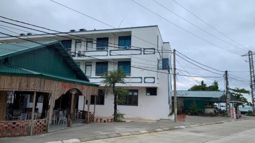 a white building with a green roof on a street at Khách Sạn Thành Trung Vàn Chảy in Quang Ninh