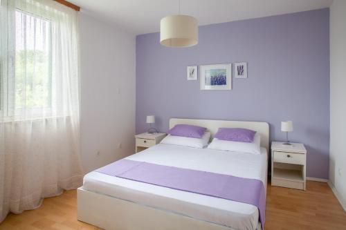a white bedroom with a large bed with purple pillows at Apartments Chiara in Korčula
