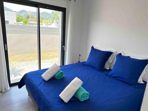 un lit bleu avec deux oreillers et une grande fenêtre dans l'établissement Corsica Suttana Vacanze, à Lecci