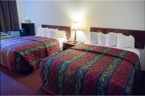 a hotel room with two beds and a table with a lamp at Marshall Lodge By OYO Hwy 65 in Marshall