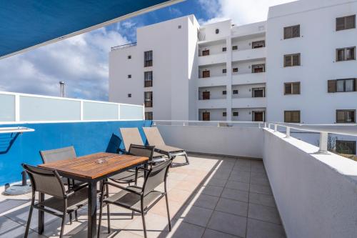 a balcony with a wooden table and chairs on a building at Apartamentos Cel Blau in Es Cana