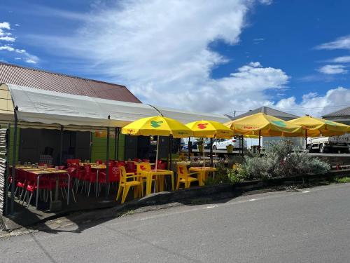 a restaurant with tables and yellow chairs and umbrellas at Studio Au Coeur de Grand Ilet - Chez Tania! in Salazie