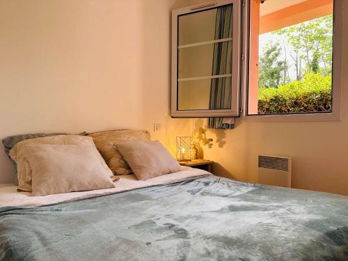 - un lit avec deux oreillers dans une chambre dotée d'une fenêtre dans l'établissement Les Palmiers Appartement, à Grimaud