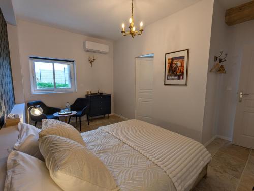 a bedroom with a bed and a chair and a window at Les Pierres Douces in Champniers