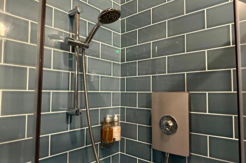 a shower in a bathroom with blue tiles at The Quarters in Weedon Bec