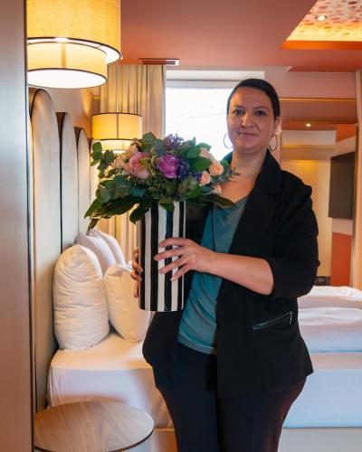 a woman holding a vase of flowers in a hotel room at Hôtel Restaurant Vaillant proche Europapark Rulantica in Sélestat