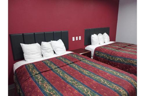 two beds in a hotel room with red walls at Marshall Lodge By OYO Hwy 65 in Marshall