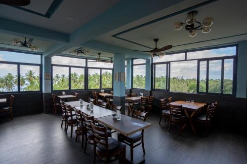 a dining room with tables and chairs and windows at Maa Thundi in Fuvahmulah