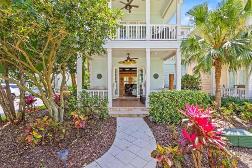 a white house with a porch with palm trees at Outriggers 18- Happy Daze in New Smyrna Beach