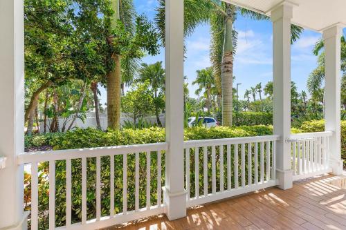 a porch with a white fence and palm trees at Outriggers 18- Happy Daze in New Smyrna Beach