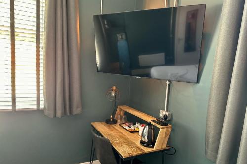 a flat screen tv on a wall with a table at The Quarters in Weedon Bec