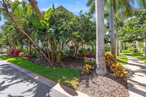 a garden with palm trees and flowers in front of a house at Outriggers 18- Happy Daze in New Smyrna Beach