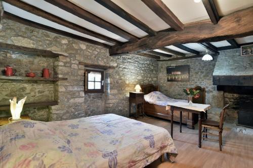 une chambre avec un lit et un mur en pierre dans l'établissement Gîte Les Croix Gibouins, à Saint-Méloir-des-Ondes