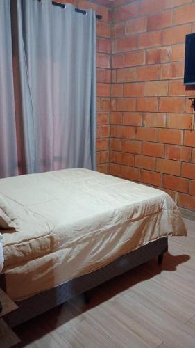 a bed in a room with a brick wall at Casa Mairinque São Roque Pq Aquático in Mairinque