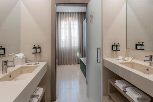 a bathroom with two sinks and two mirrors at Catalonia Atocha in Madrid