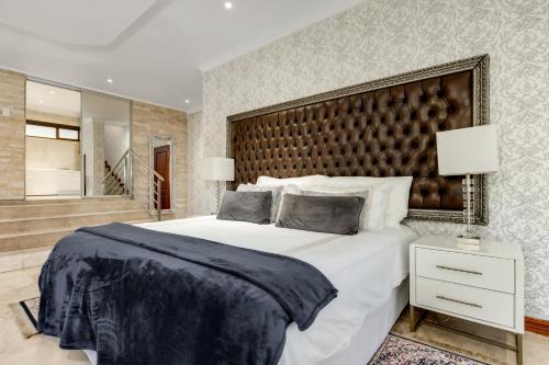 a bedroom with a large bed with a large headboard at The Diplomat in Midrand