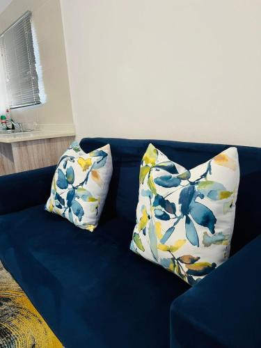 a blue couch with two pillows on it at Cozy One-bedroom Apartment near GrandPalm Resort Block 5, Gaborone, Botswana in Mogoditshane