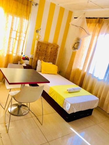a bedroom with a bed and a table and a desk at ZUNOX GUEST HOUSE in Freetown